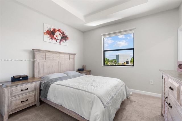 bedroom featuring a tray ceiling, light carpet, and baseboards