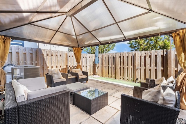 view of patio / terrace with an outdoor hangout area, fence, central AC unit, and a gazebo