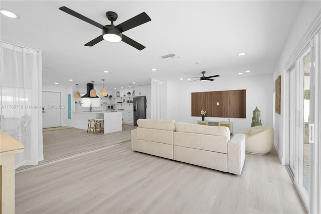 living room with recessed lighting, visible vents, light wood-style flooring, and a ceiling fan