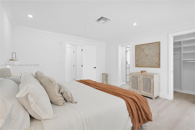 bedroom with visible vents, a walk in closet, ornamental molding, wood finished floors, and recessed lighting