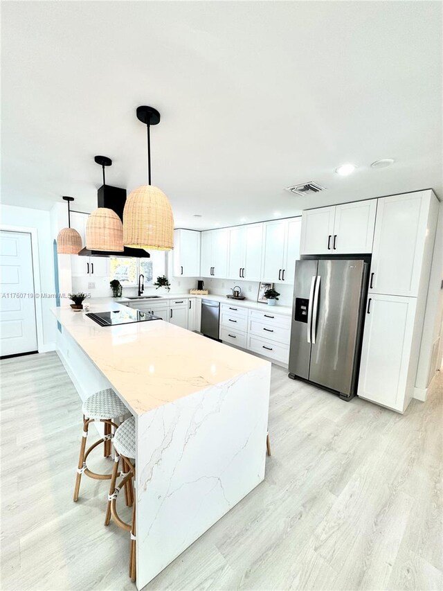 kitchen featuring visible vents, light wood-style flooring, appliances with stainless steel finishes, white cabinetry, and a sink