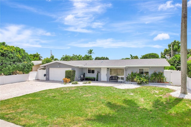 ranch-style home featuring a front lawn, fence, stucco siding, driveway, and an attached garage