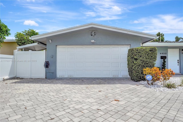 garage with decorative driveway and fence
