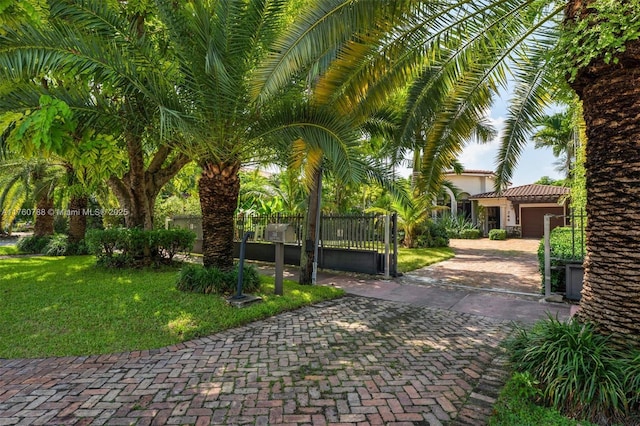 surrounding community featuring a lawn, a gate, decorative driveway, fence, and a garage