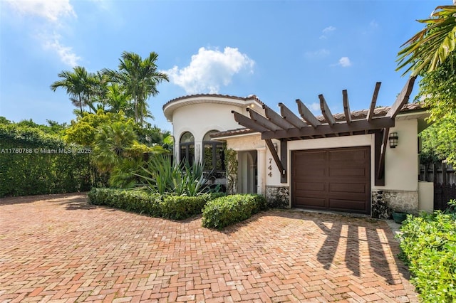 mediterranean / spanish home featuring decorative driveway, an attached garage, stone siding, and stucco siding