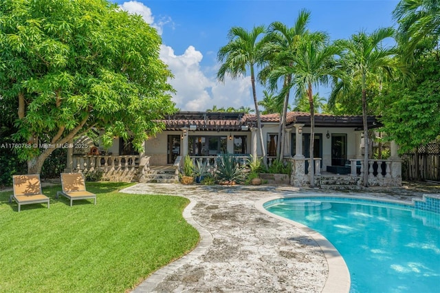 rear view of house with stucco siding, a lawn, a tile roof, a fenced in pool, and a patio area