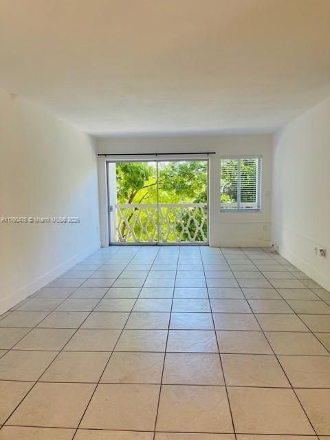 spare room with light tile patterned floors and baseboards