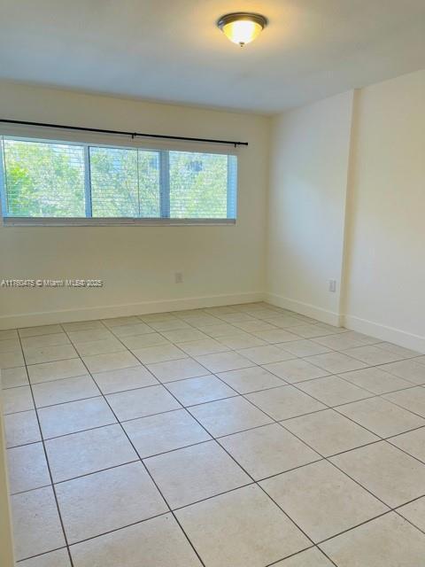 spare room with light tile patterned floors and baseboards