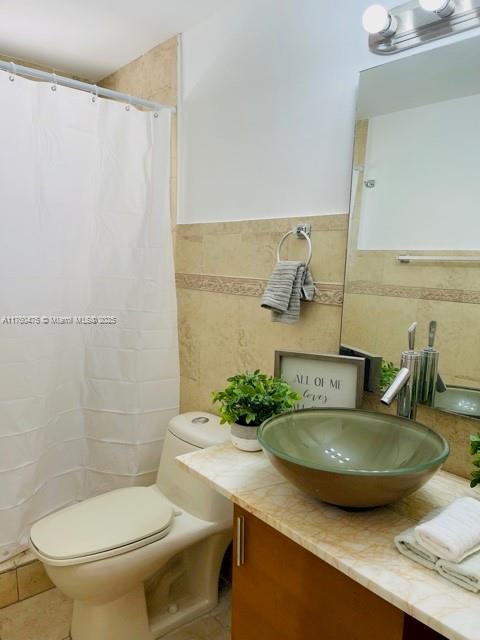 bathroom with tile patterned floors, toilet, tile walls, and vanity