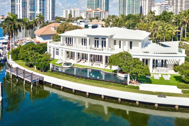 rear view of house with a city view, a balcony, a jacuzzi, and a water view