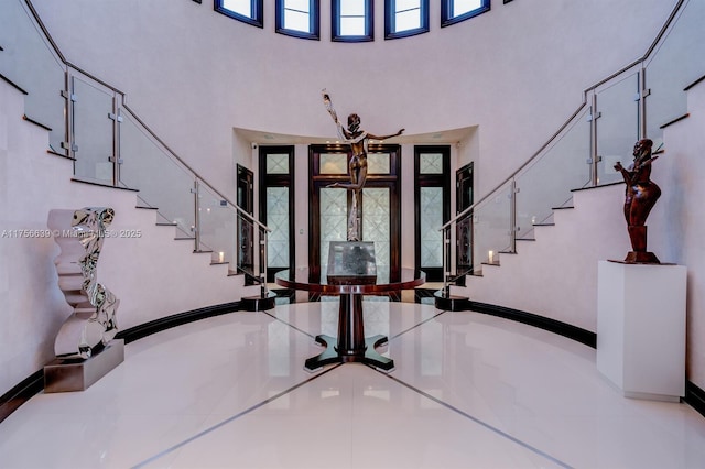 foyer entrance with stairway, french doors, a high ceiling, and baseboards