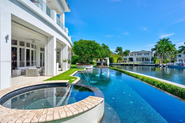 view of pool with a patio area, a water view, a ceiling fan, and a pool with connected hot tub