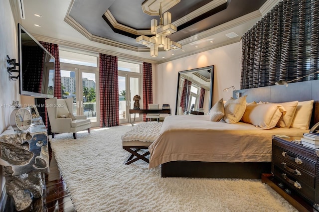 bedroom with a ceiling fan, a tray ceiling, wood finished floors, french doors, and crown molding