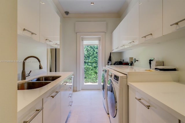 clothes washing area featuring washer and clothes dryer, cabinet space, and a sink