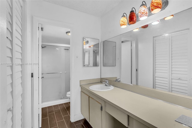 bathroom featuring vanity, baseboards, wood finish floors, a stall shower, and toilet