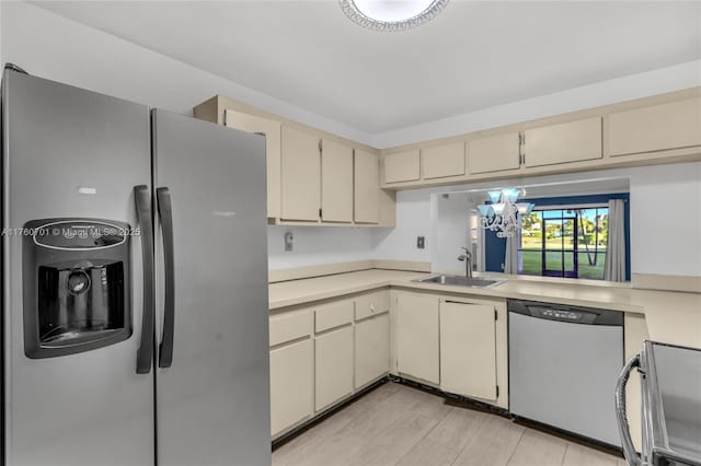 kitchen with cream cabinets, stainless steel appliances, light countertops, and a sink