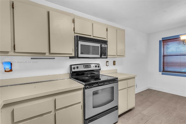 kitchen featuring cream cabinetry, appliances with stainless steel finishes, light countertops, and light wood-style floors