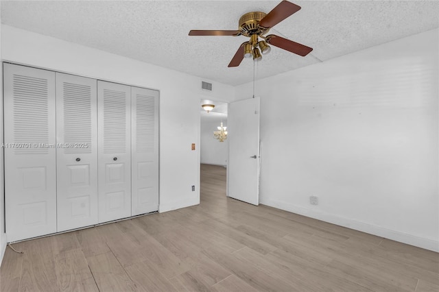 unfurnished bedroom featuring visible vents, a textured ceiling, a closet, light wood finished floors, and baseboards