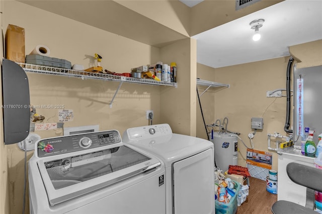 laundry room featuring wood finished floors, visible vents, laundry area, water heater, and washer and dryer