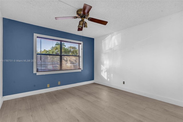 empty room featuring a textured ceiling, baseboards, and wood finished floors