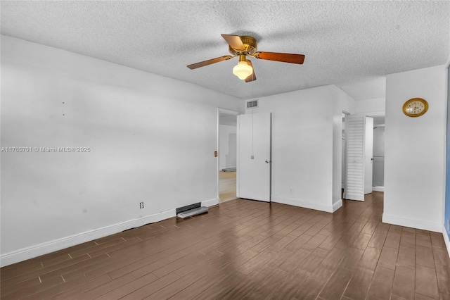 unfurnished bedroom featuring dark wood finished floors, visible vents, a textured ceiling, and baseboards