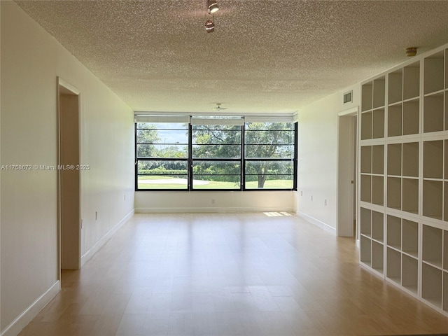 1504 S Whitehall Dr Unit 206, Davie, FL 33324 - unfurnished room featuring a textured ceiling, healthy amount of natural light, wood finished floors, and a smoke detector