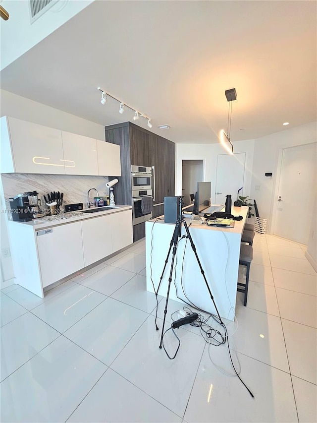 kitchen with light tile patterned floors, decorative light fixtures, rail lighting, white cabinetry, and modern cabinets