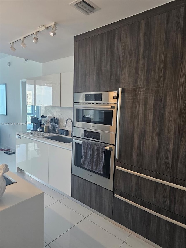 kitchen with modern cabinets, visible vents, track lighting, double oven, and dark brown cabinets