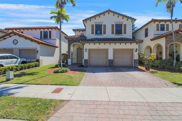 mediterranean / spanish-style home featuring stucco siding, decorative driveway, stone siding, an attached garage, and a tiled roof