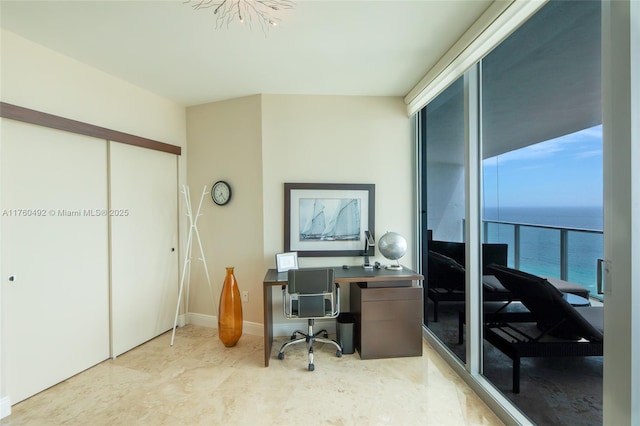 office area with a wall of windows, baseboards, and a water view