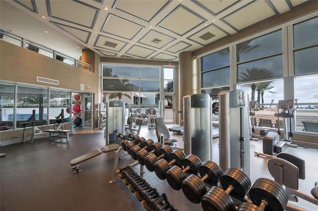 gym with visible vents, coffered ceiling, a towering ceiling, and floor to ceiling windows