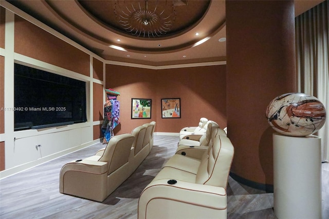 cinema featuring recessed lighting, baseboards, a tray ceiling, and wood finished floors