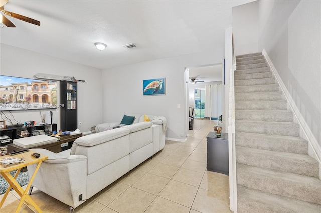 living area with a ceiling fan, stairs, light tile patterned flooring, and visible vents