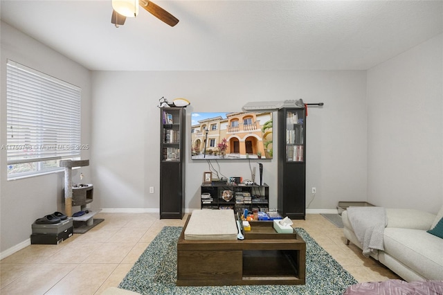living area with light tile patterned flooring, ceiling fan, and baseboards