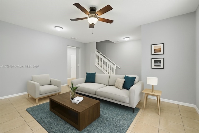living room featuring baseboards, a ceiling fan, stairs, and light tile patterned flooring