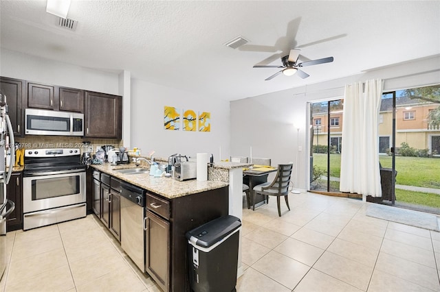 kitchen featuring visible vents, appliances with stainless steel finishes, a sink, light tile patterned floors, and a peninsula