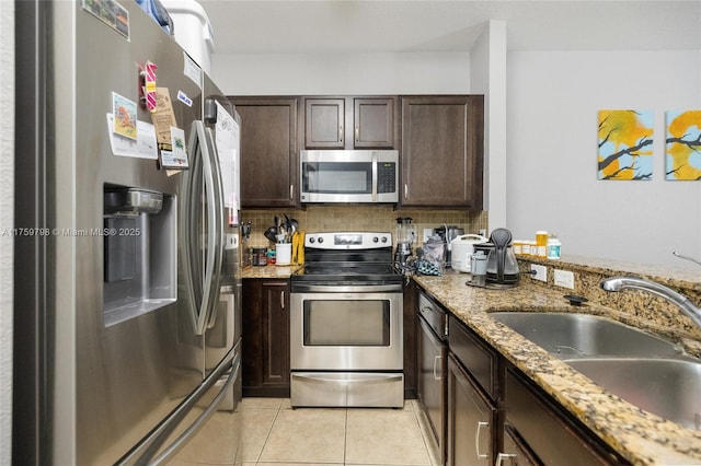 kitchen with a sink, dark brown cabinetry, light tile patterned flooring, and stainless steel appliances