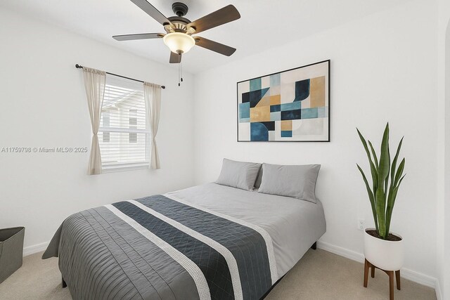 bedroom with a ceiling fan, baseboards, and light carpet
