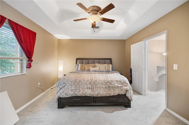 carpeted bedroom with a raised ceiling, baseboards, a ceiling fan, and visible vents