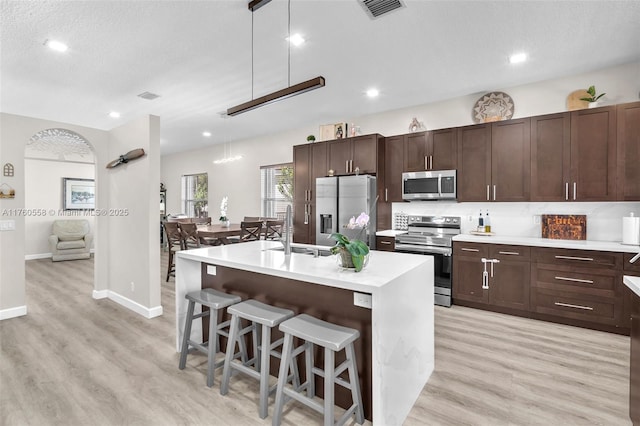 kitchen featuring visible vents, a sink, light countertops, appliances with stainless steel finishes, and a kitchen breakfast bar