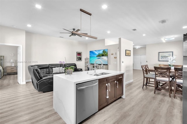 kitchen with open floor plan, dishwasher, an island with sink, light countertops, and a sink