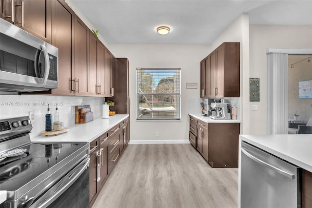 kitchen with backsplash, baseboards, light wood-type flooring, light countertops, and appliances with stainless steel finishes