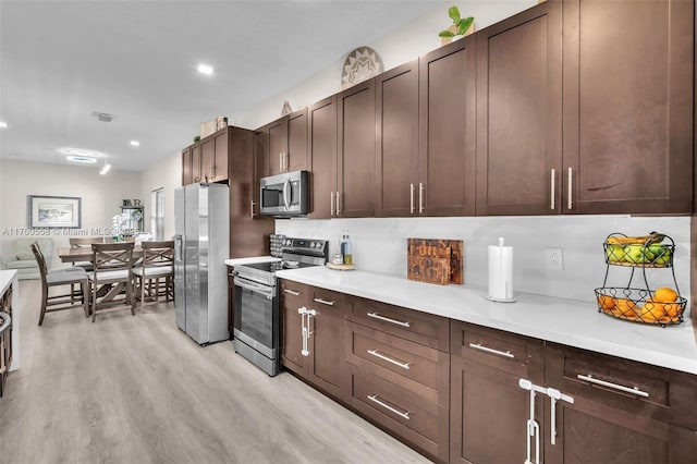 kitchen with visible vents, dark brown cabinetry, light countertops, light wood-style flooring, and stainless steel appliances