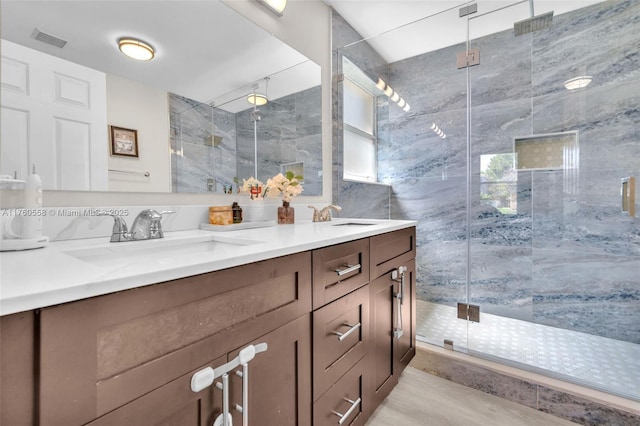 bathroom with a shower stall, double vanity, visible vents, and a sink