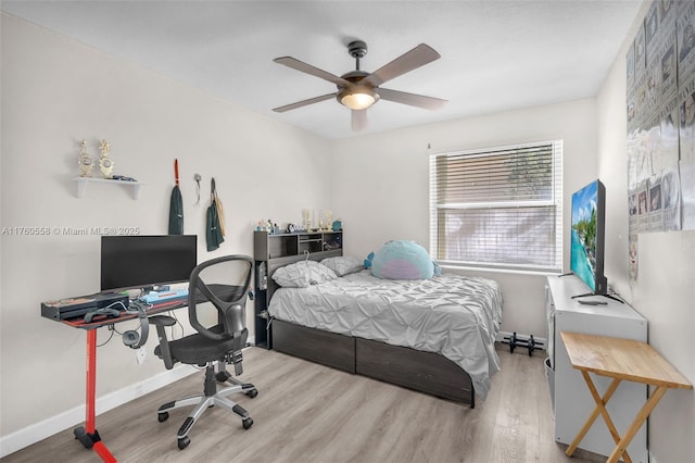 bedroom with ceiling fan, a baseboard heating unit, baseboards, and wood finished floors