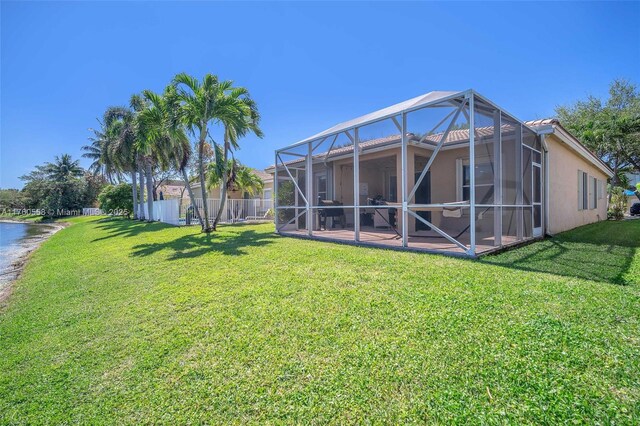 view of yard with a lanai, fence, a patio, and a water view