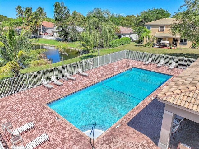 pool featuring a patio, fence, a lawn, and a water view