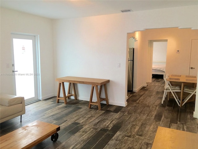 interior space with baseboards, visible vents, and dark wood-style flooring