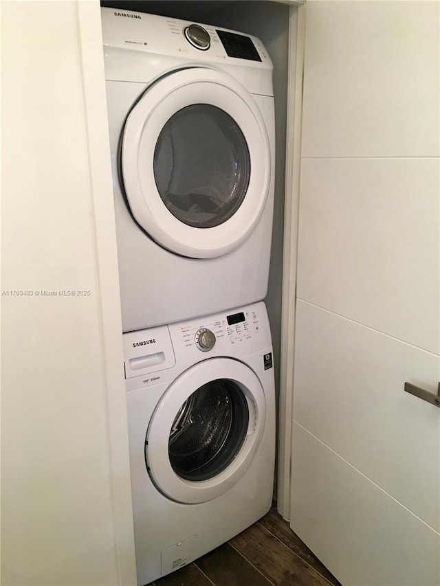 washroom featuring dark wood-style floors, laundry area, and stacked washer / dryer