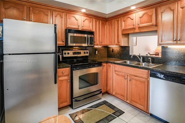 kitchen with dark countertops, decorative backsplash, stainless steel appliances, and a sink